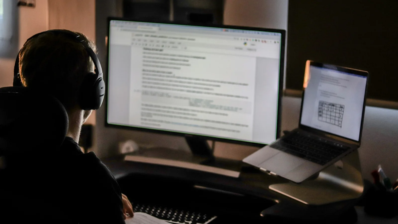 WordPress developer working on a client website at a desk with a laptop and monitor